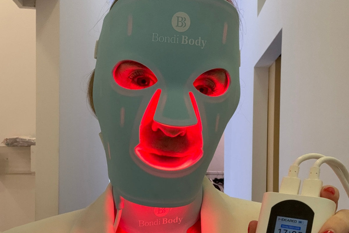 Trish, founder of Bondi Body, wearing the Bondi Body LED face mask and the neck and chest mask with the red light on